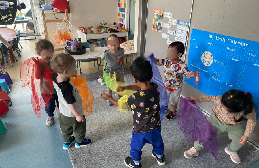 children dancing to music with coloured scarves in our cocoon club room