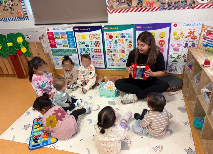 infants benefitting from music in childcare while educator plays the accordion