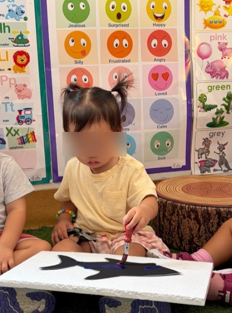 infant holding a paintbrush designed for small children