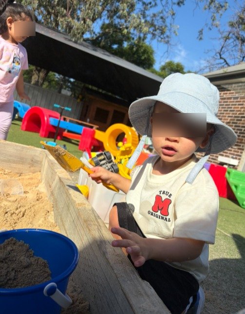 a toddler playing with sand at Kiddie Garden Daycare and Preschool Parramatta