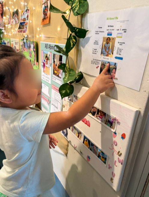 toddler identifying herself on a family poster at daycare