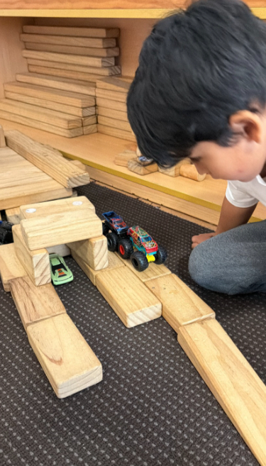 preschool child building with blocks and cars as a stem activity