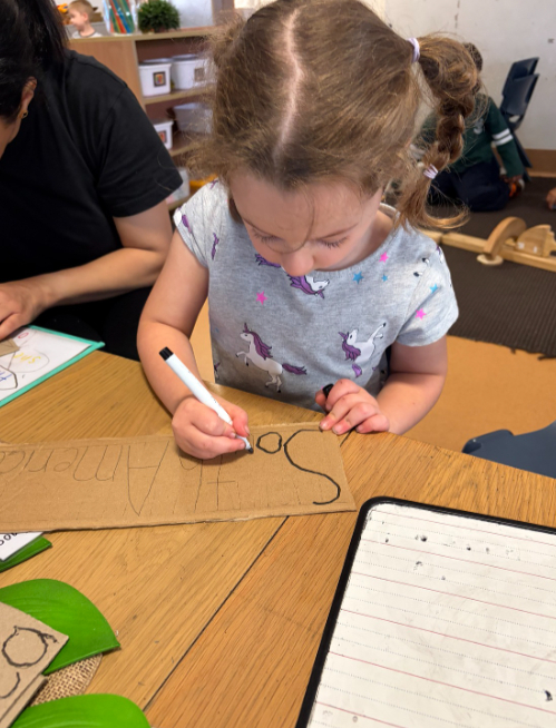 child writing at preschool in preparation for kindergarten