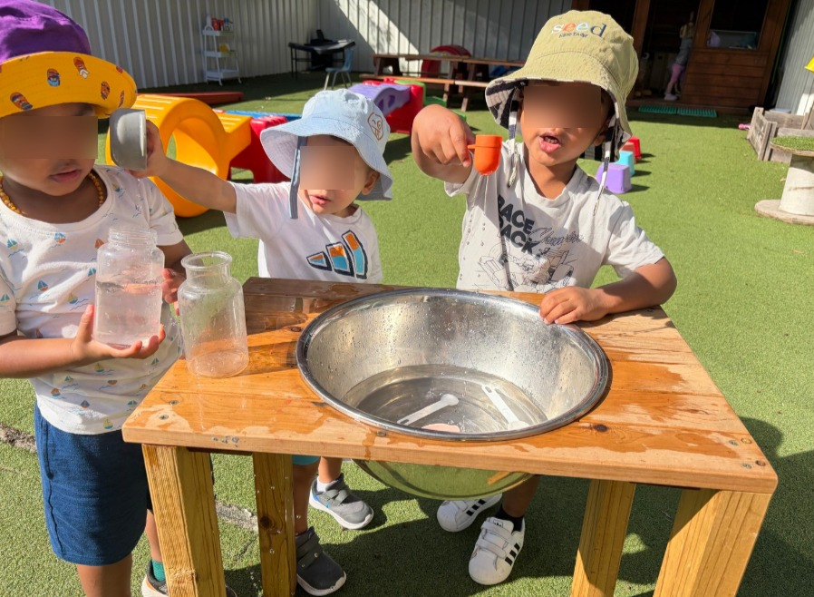 preschoolers playing with water with measuring cups at kiddie garden preschool parramatta